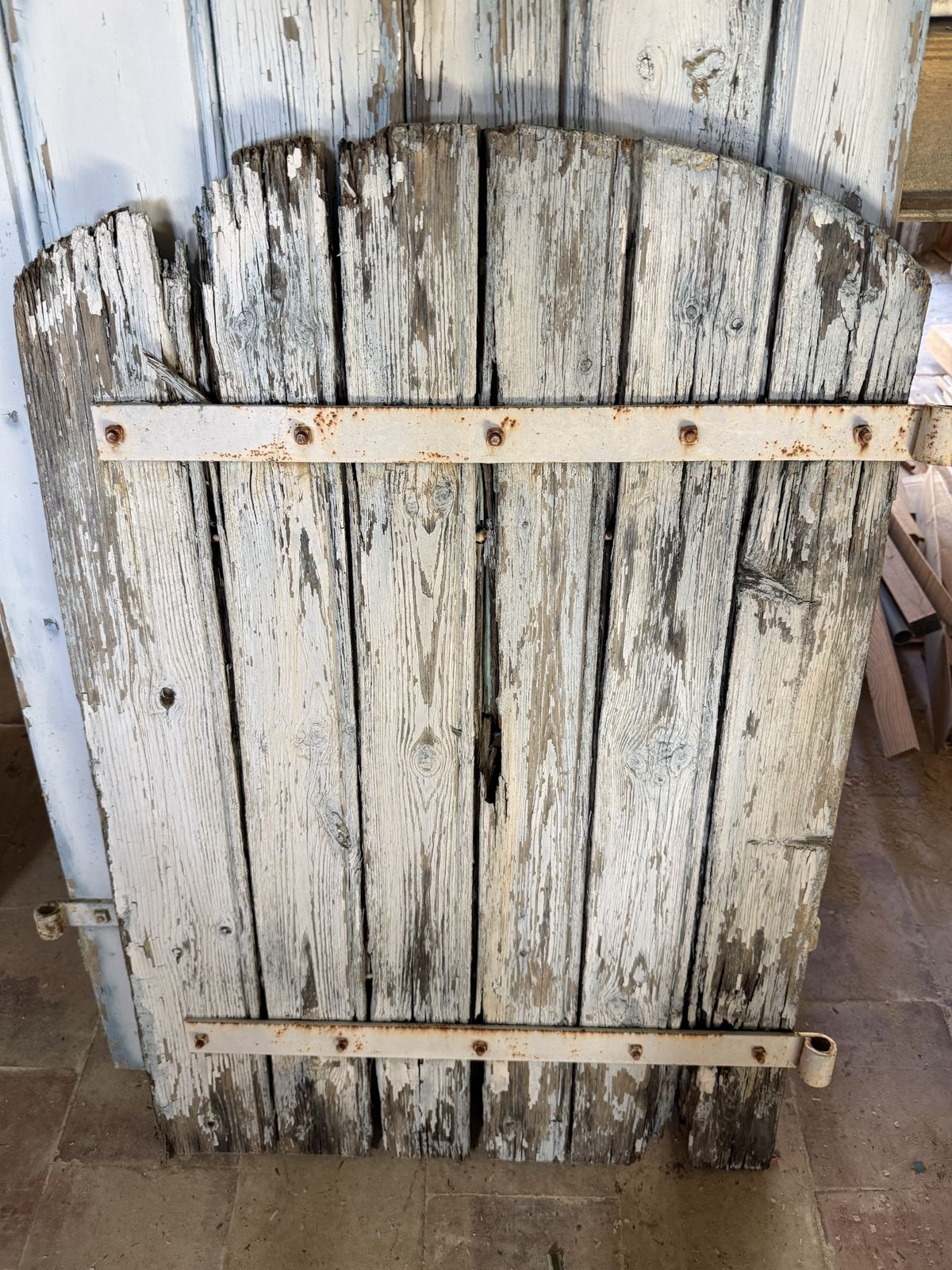 Gammal fönsterlucka i trä med flagnande färg och rostiga beslag